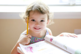 Little toddler girl writing at school desk, homework