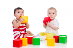 two infants playing together with soft building blocks